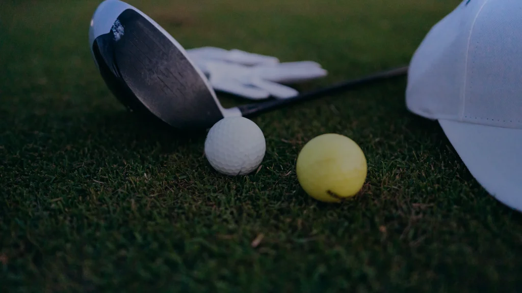Balle de golf et driver posés sur l'herbe d'un parcours