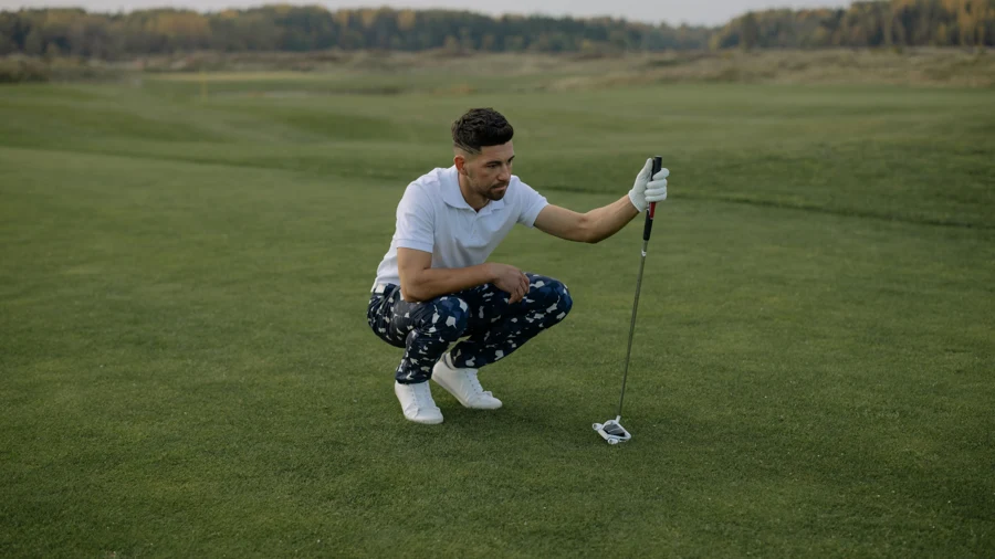 Golfeur accroupi sur le parcours qui lit son coup à l'aide de son club