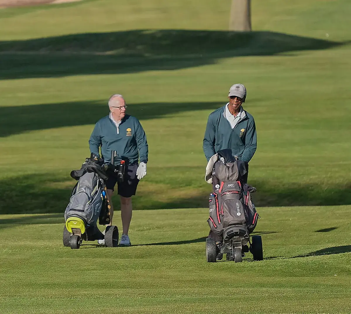 Deux golfeurs poussant leur sac de golf sur un chariot, sur un fairway