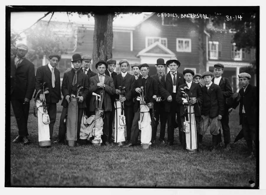 Groupe de jeunes caddies posant avec des sacs de golf sur un gazon, vers 1910